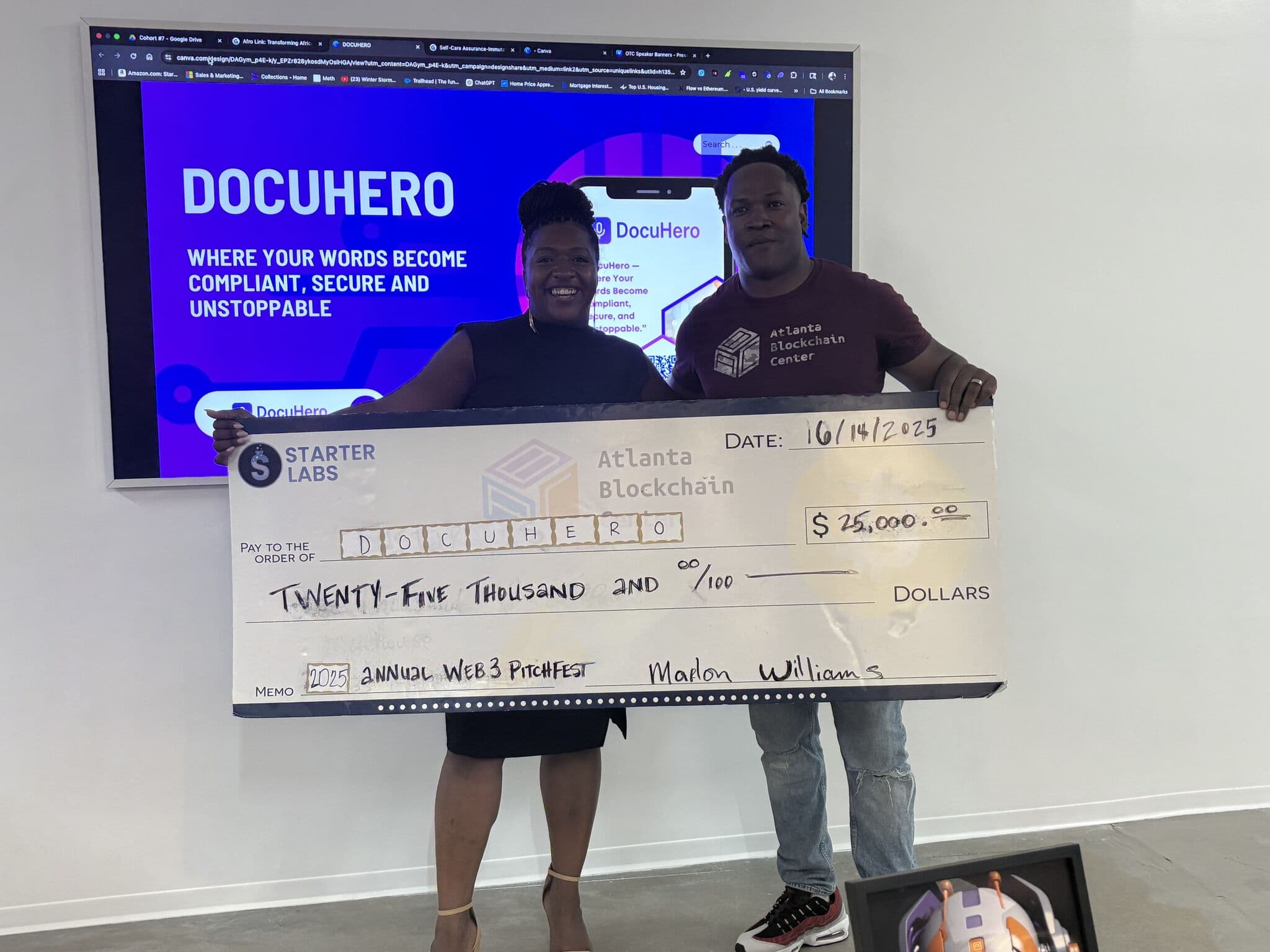 Latia Williams holding the $25,000 Pitchfest check with the Atlanta Blockchain Center, in front of the DocuHero pitch deck